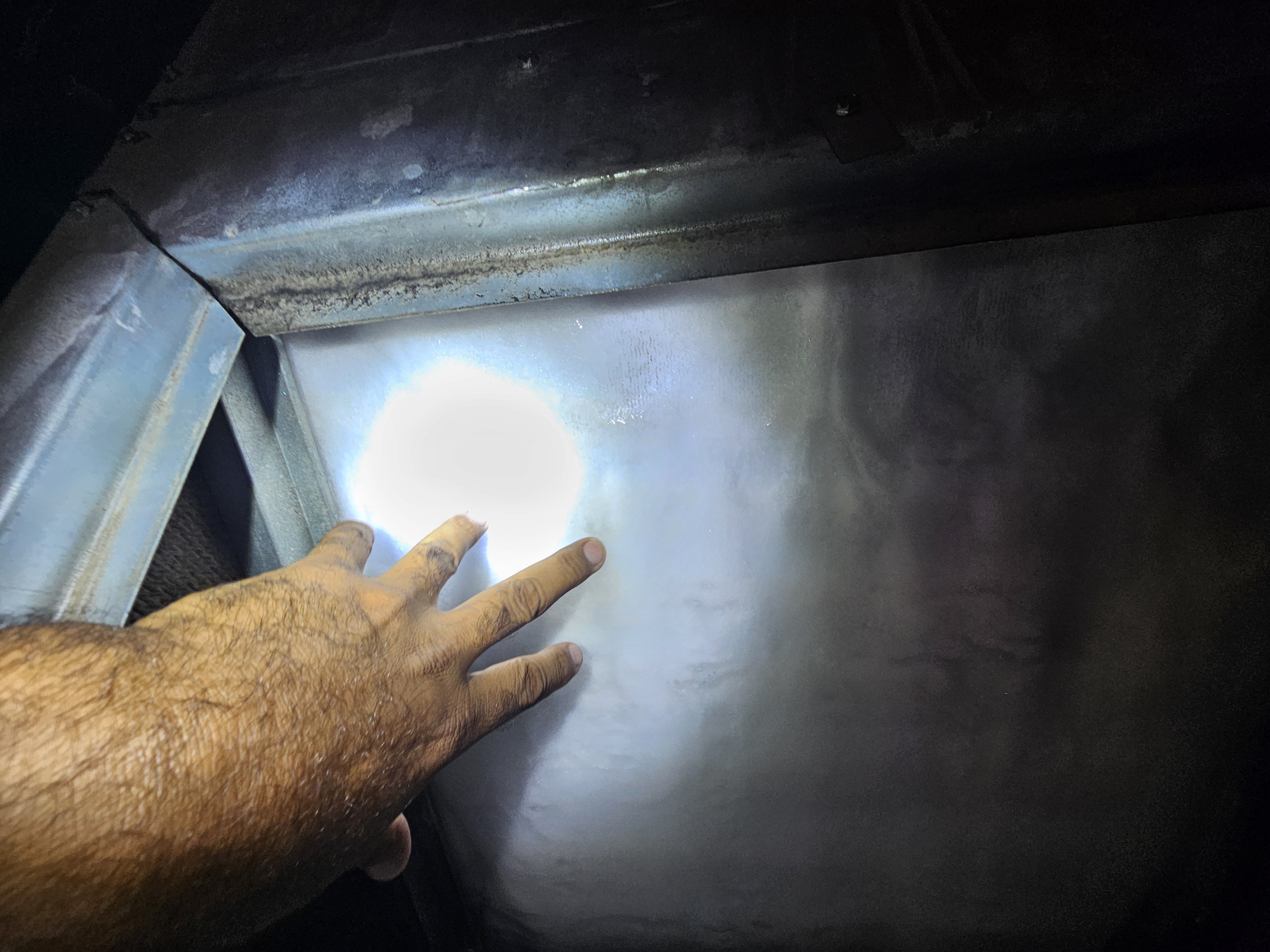A Plus Air technician inspecting an HVAC rooftop package unit coil