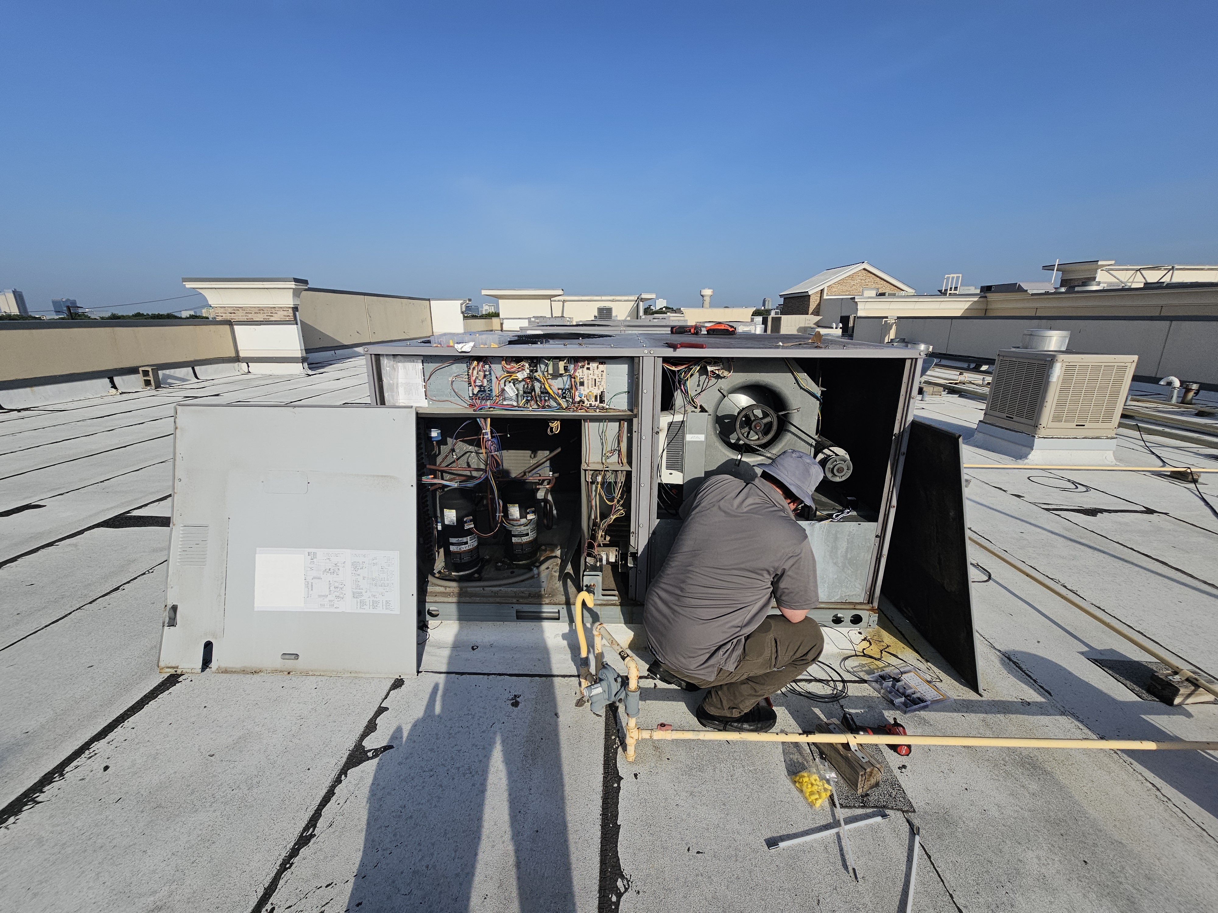 A Plus Air technician servicing a rooftop commercial HVAC unit in Allen, TX